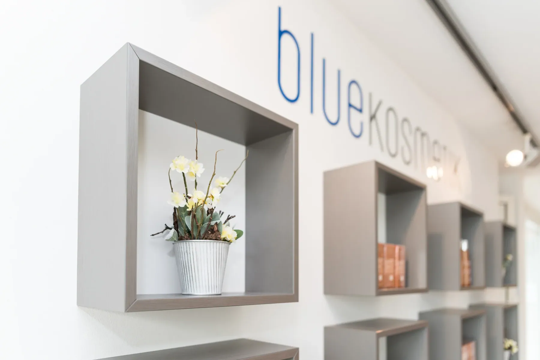 Regal mit Pflegeprodukten und blue Kosmetik Schriftzug